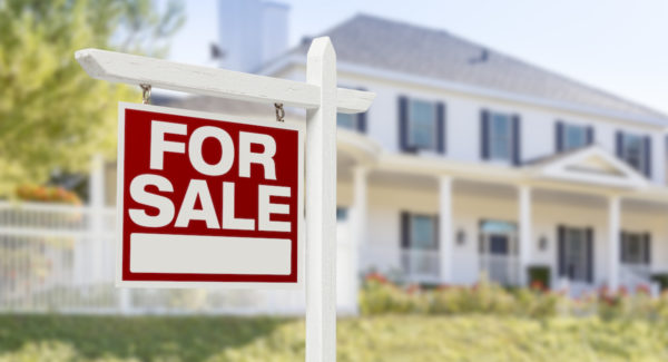 Home For Sale Real Estate Sign in Front of Beautiful New House.